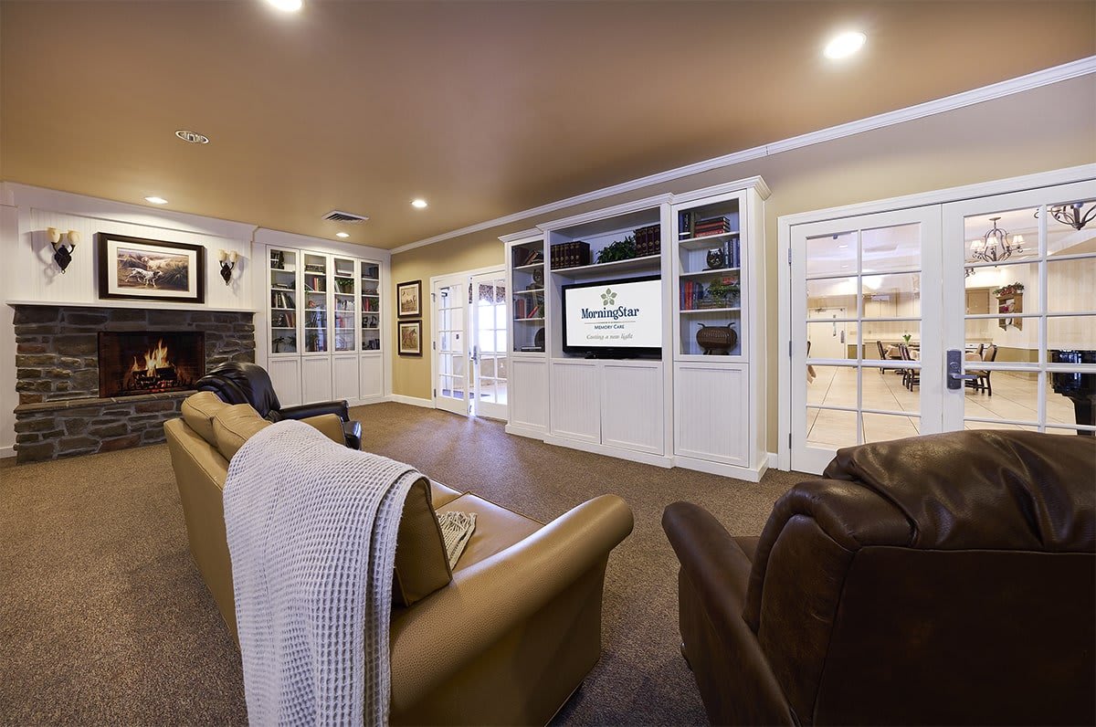 A cozy living room featuring a home theater setup with bookshelves and comfortable seating.