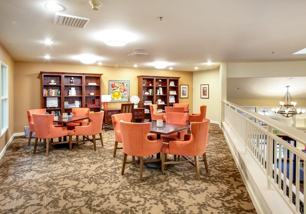 A cozy indoor library with tables, chairs, and bookshelves.