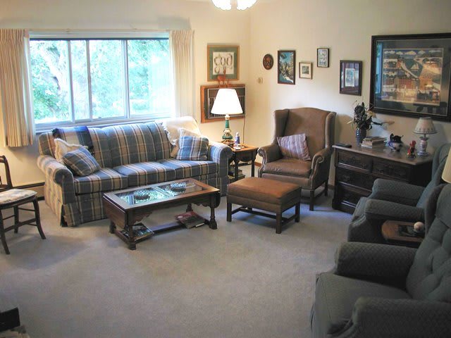 A cozy living room with a sofa, armchair, and coffee table, adorned with decorative elements.
