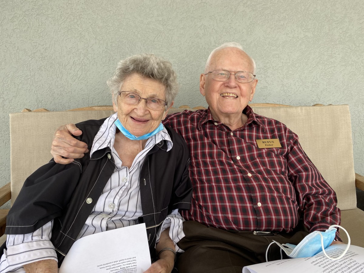 An elderly couple sitting together, smiling and enjoying each other's company.