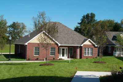A suburban brick house with a well-maintained lawn and clear blue sky.