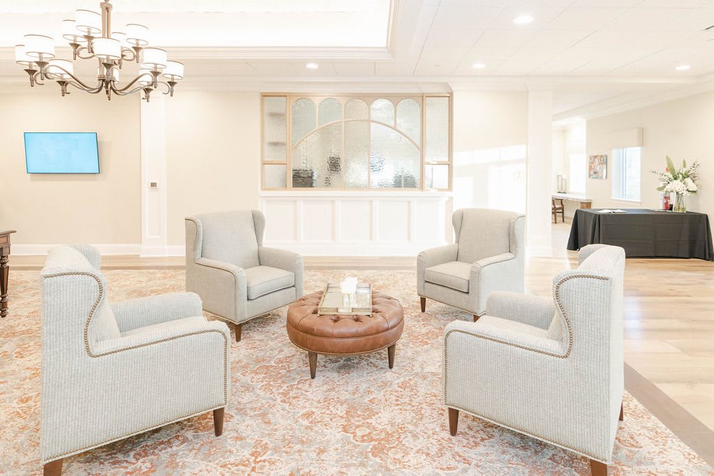 A cozy living room with four armchairs and a coffee table, decorated in neutral tones.
