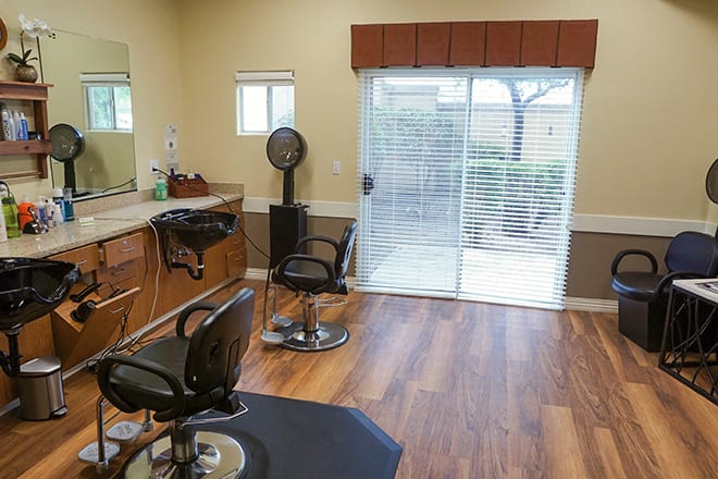 A modern hair salon with barber chairs, mirrors, and a hairdryer in a bright room with wooden flooring.