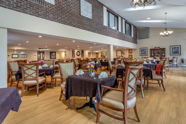 A spacious and elegantly decorated dining area with neatly arranged tables and chairs under a high ceiling.