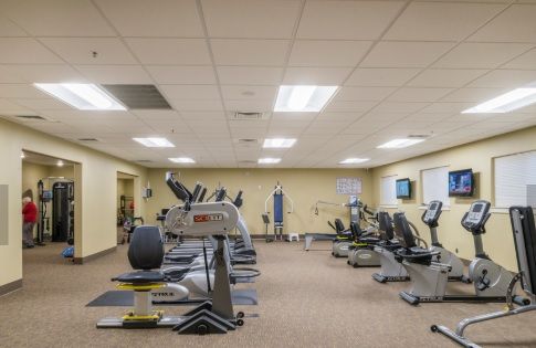 A well-equipped gym with various exercise machines including treadmills and stationary bikes.