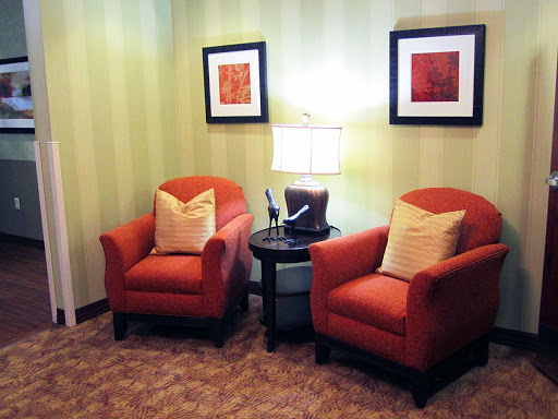 A cozy corner featuring two orange chairs, a side table, and wall art.
