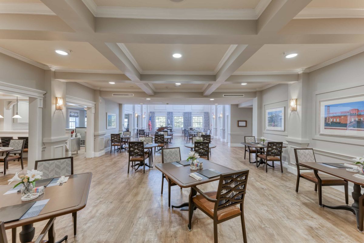 A modern, spacious dining area with elegant tables and chairs, lit by ceiling lights.