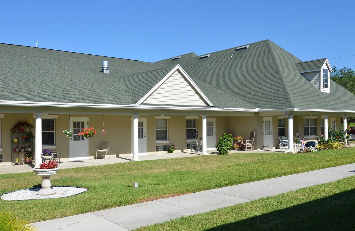 A single-story house with a green roof and a well-maintained front lawn.