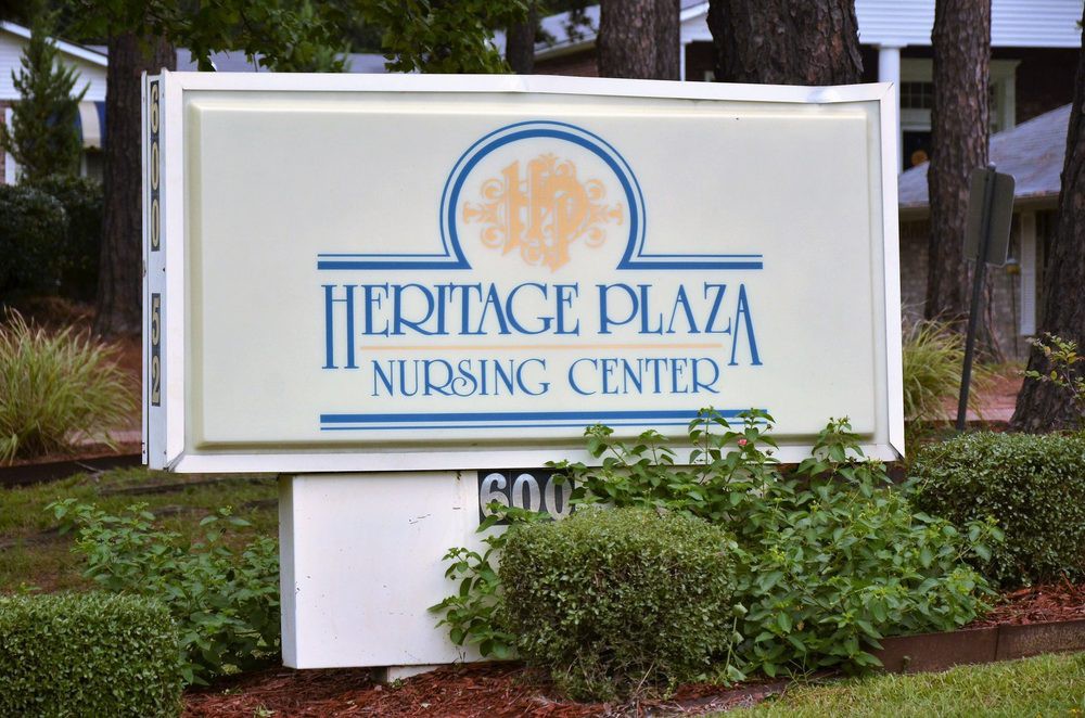 Sign for Heritage Plaza Nursing Center surrounded by greenery.