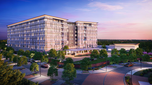 A modern residential building surrounded by greenery, captured at sunset.