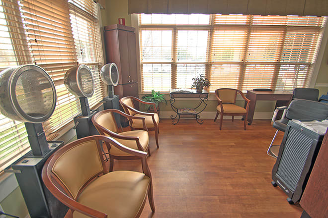 A cozy waiting room with wooden floors and natural light streaming through large windows.