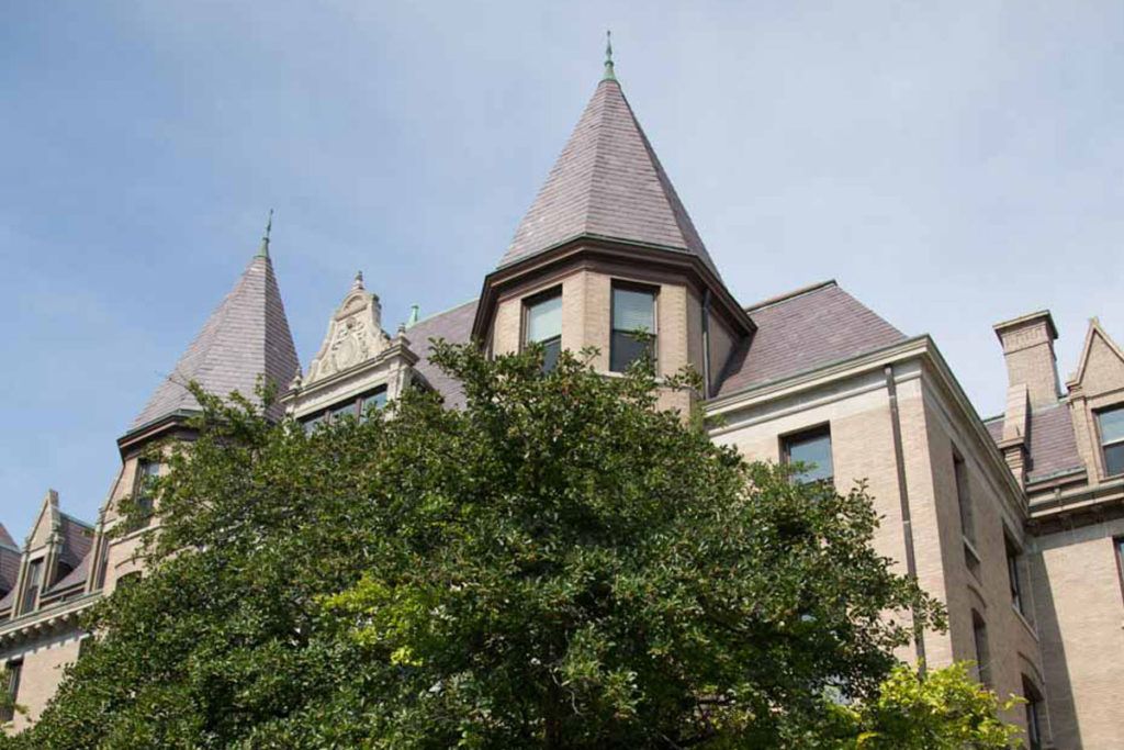 A historic building with turrets partially obscured by trees.