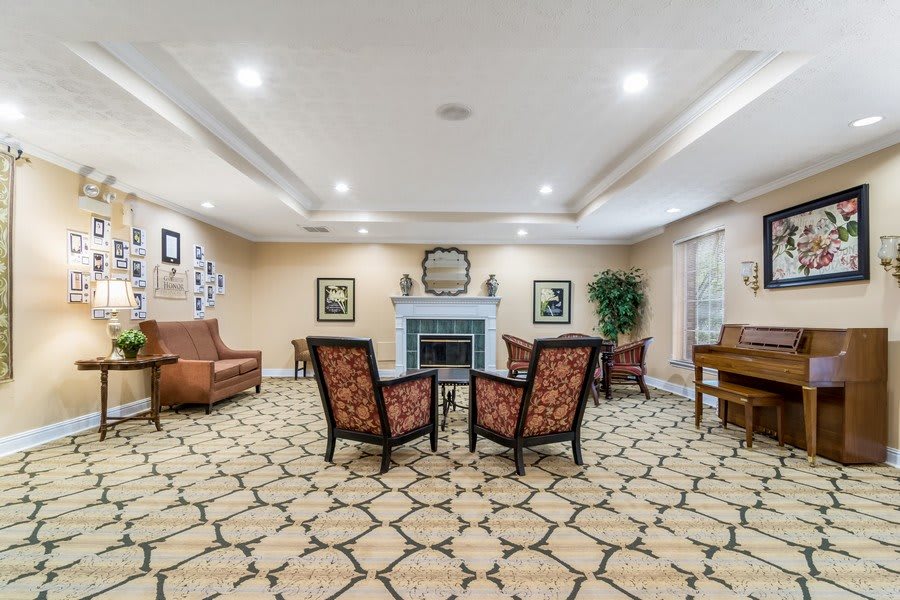 A cozy living room with a central fireplace, surrounded by upholstered armchairs and elegant decor.