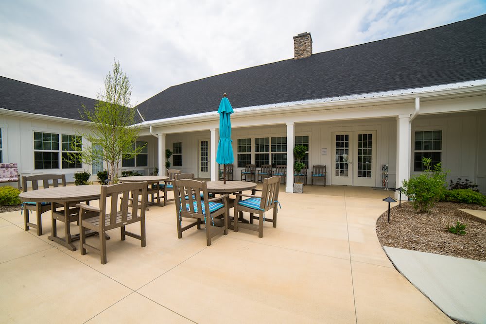 A spacious patio with tables, chairs, and an umbrella outside a building.