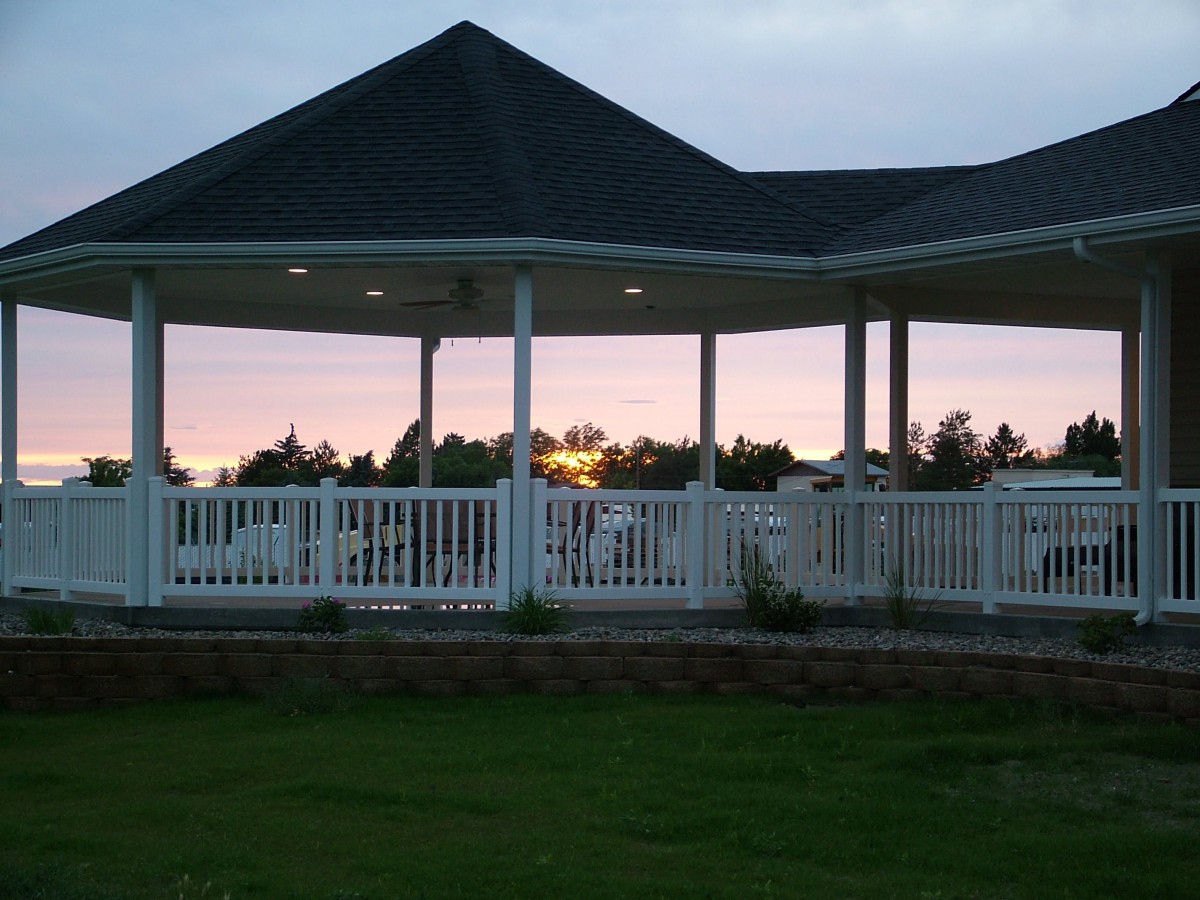 A scenic sunset view through a gazebo with a white fence.