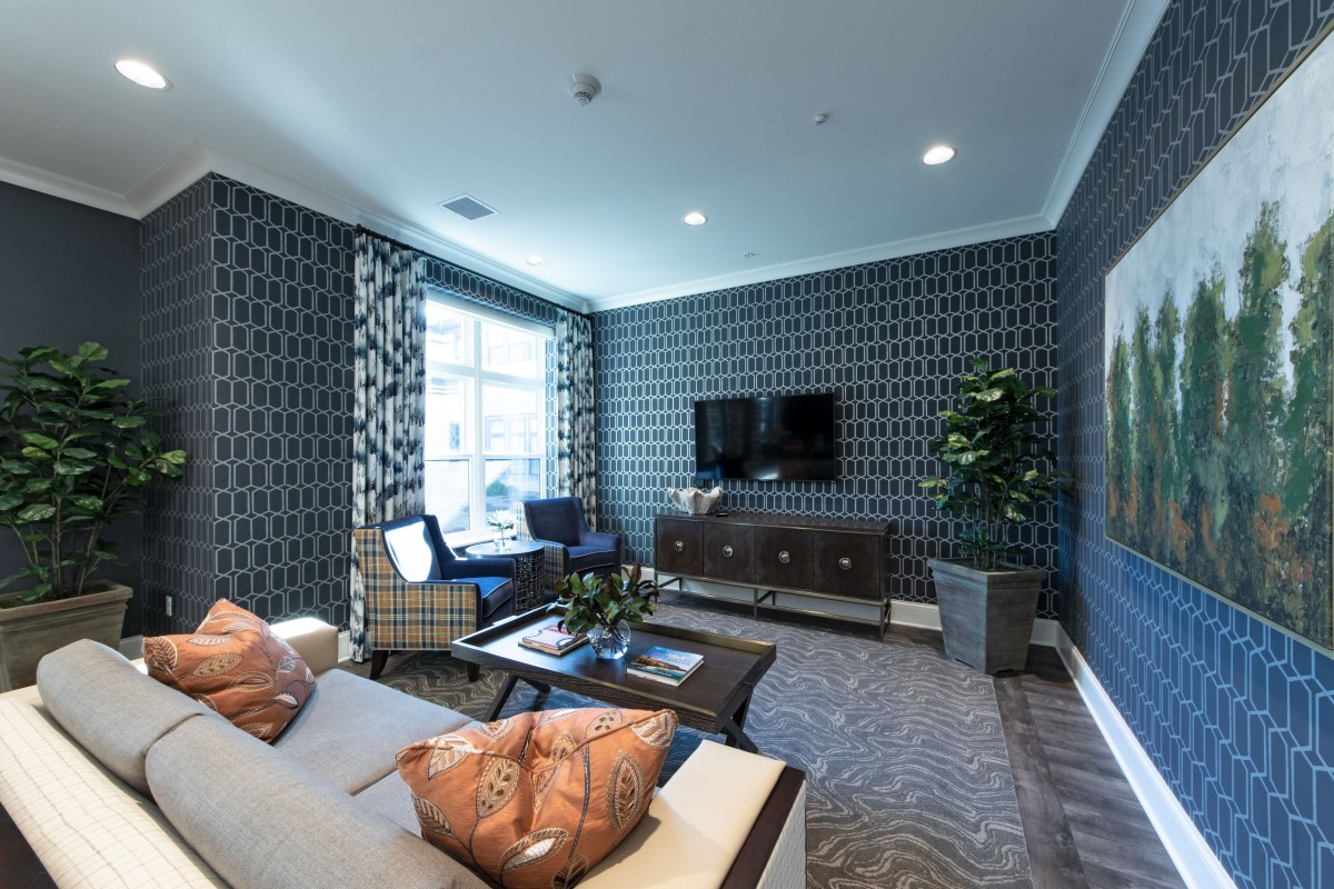 A modern living room with stylish patterned wallpaper and contemporary furnishings.