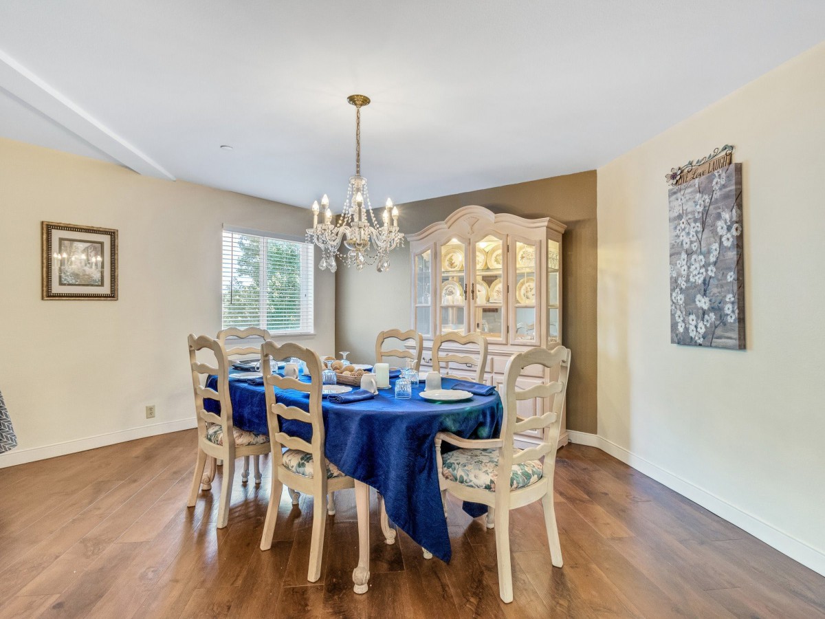 A dining room featuring a wooden floor, blue tablecloth, and elegant chandelier.