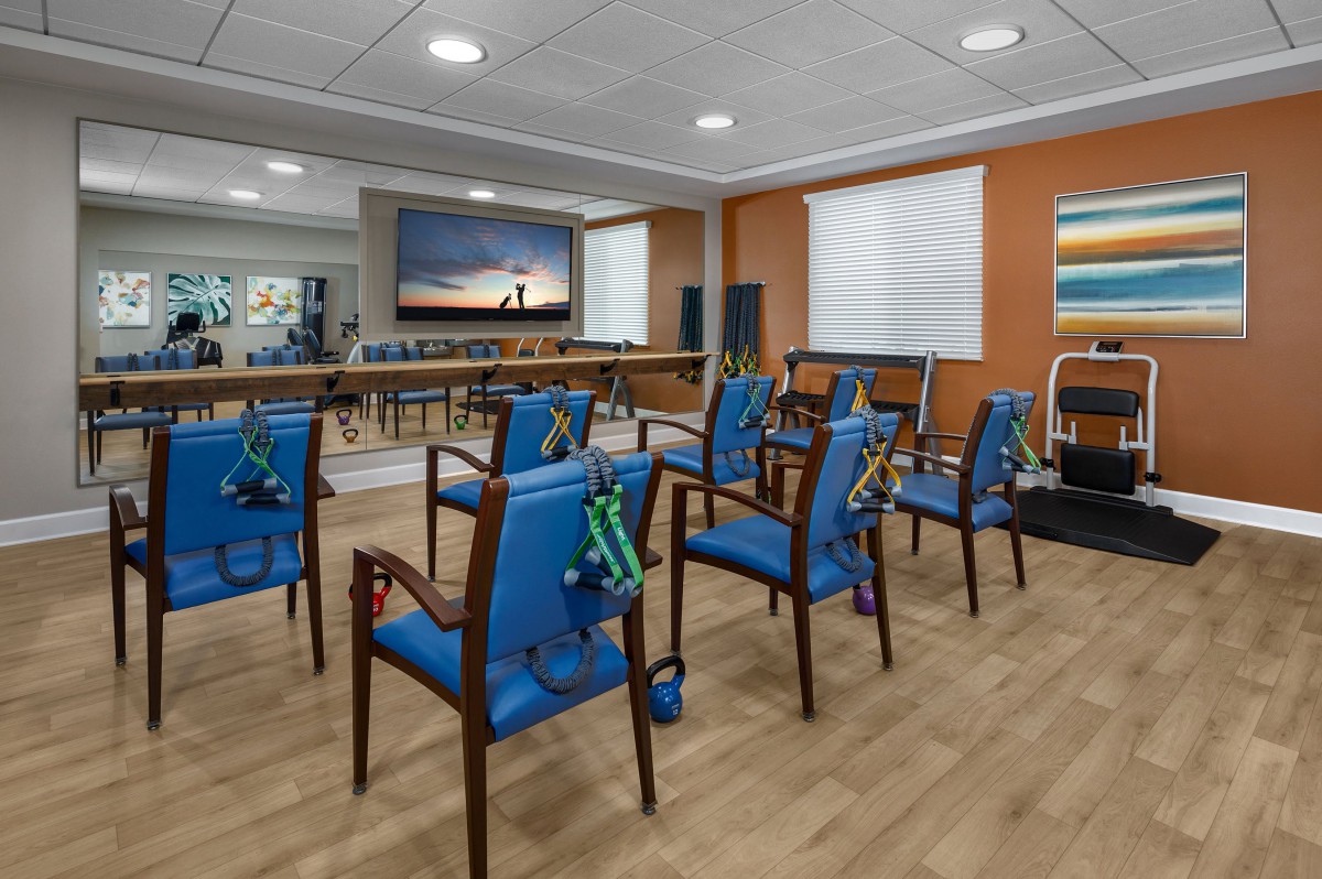 A well-organized conference room featuring blue upholstered chairs arranged in rows, with warm lighting and a decorative wall art piece.