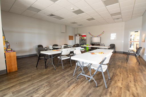 A spacious meeting room equipped with tables and chairs, ready for a group gathering.