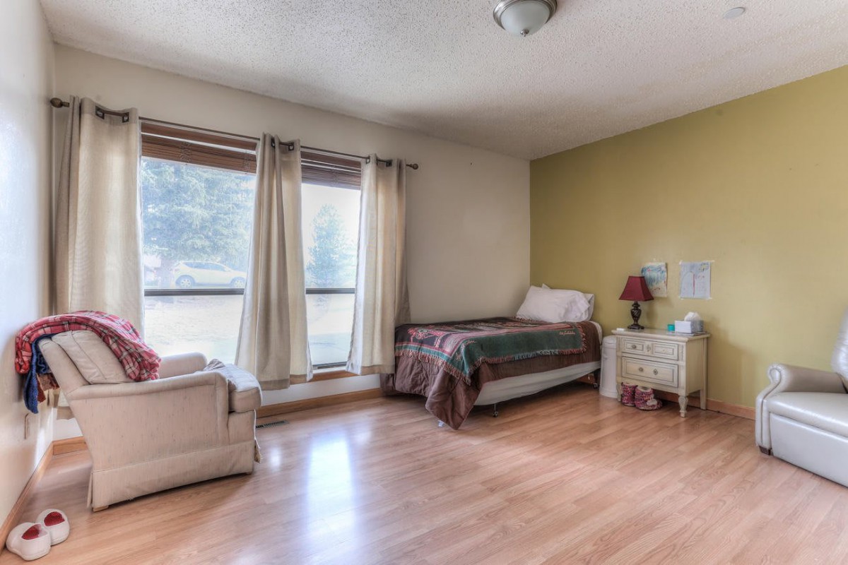 A cozy bedroom with a single bed, armchair, and large windows letting in natural light.