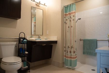 A modern bathroom featuring a sink with a mirror above it and a shower area with a colorful curtain.