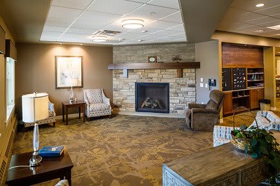 A cozy living room interior featuring a stone fireplace, comfortable armchairs, and warm decor.
