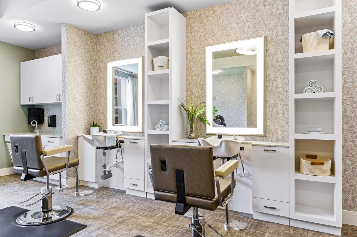 A modern beauty salon interior with styling stations and illuminated mirrors.