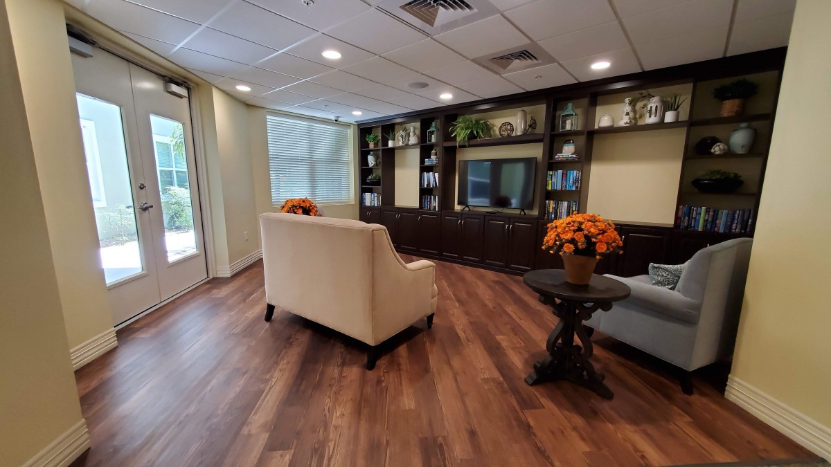 A modern living room with wood flooring, comfortable seating, and decorative shelves.