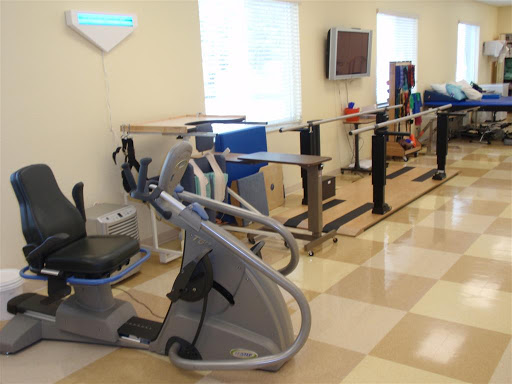 A well-equipped rehabilitation and exercise room featuring various fitness machines and therapy bars.