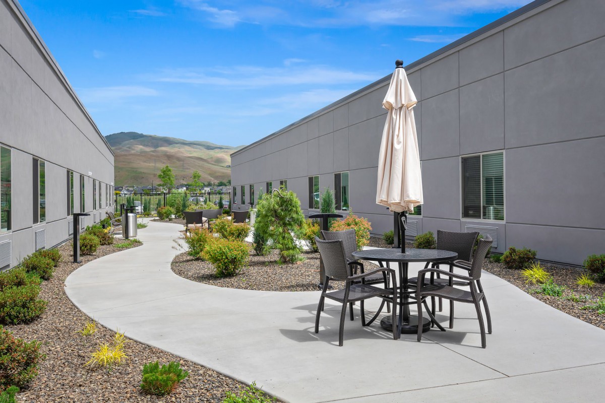 A modern courtyard with outdoor seating, surrounded by landscaping and buildings.