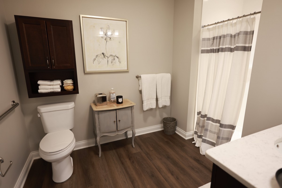A neatly organized bathroom with modern decor and wooden floors.