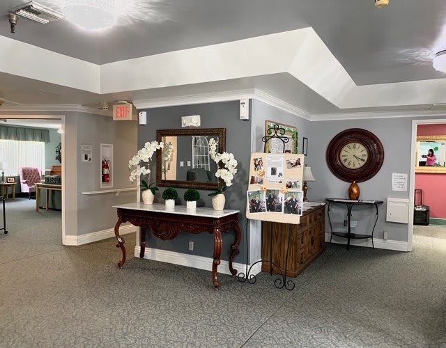 A well-decorated lobby area featuring a mirror, plants, and a large wall clock.