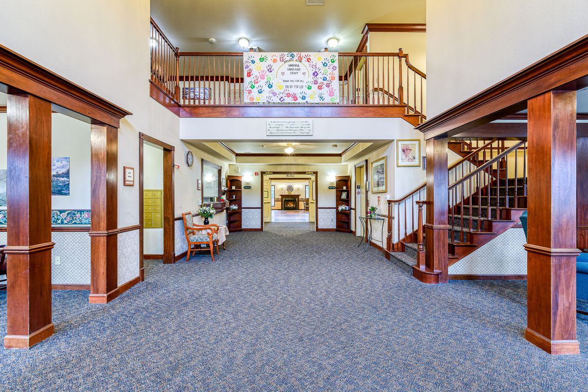 Spacious and welcoming lobby area with a central seating arrangement and carpeted flooring, featuring staircases on either side.