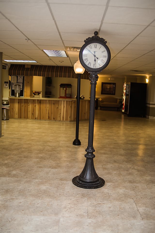 A vintage-style standing clock and lamp in the lobby of a reception area.