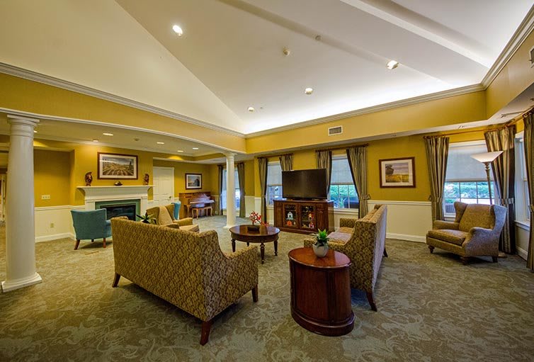 A spacious, elegantly decorated living room with comfortable seating and a large television.