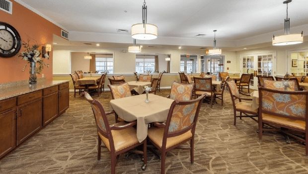 An elegantly designed dining area with neatly arranged tables and chairs under warm lighting.