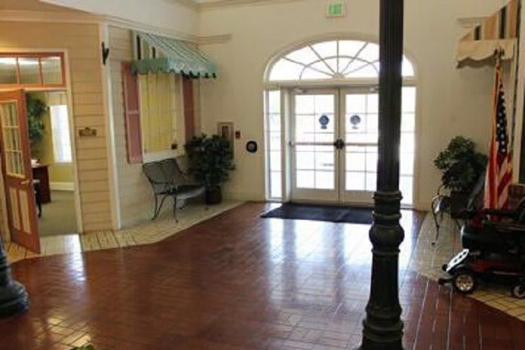A quiet indoor lobby with a bench, plant, and large glass doors.