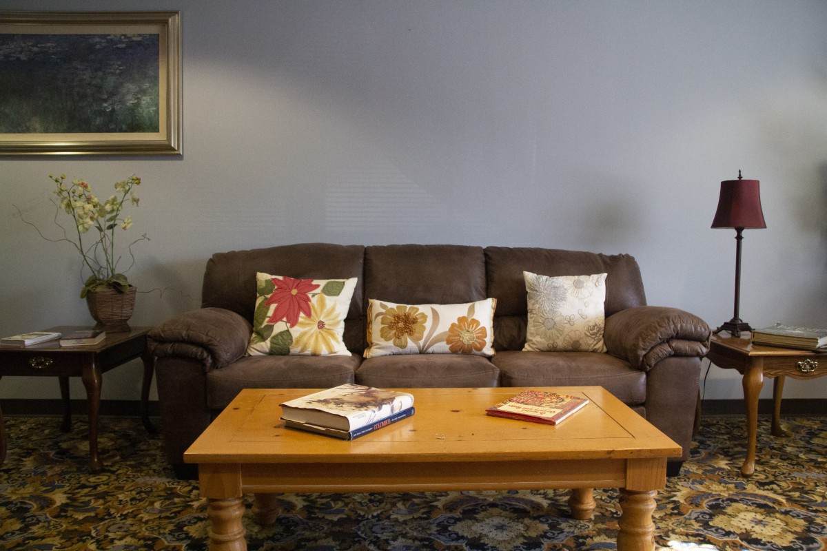 A cozy living room setup with a brown sofa adorned with patterned cushions and a wooden coffee table holding books.