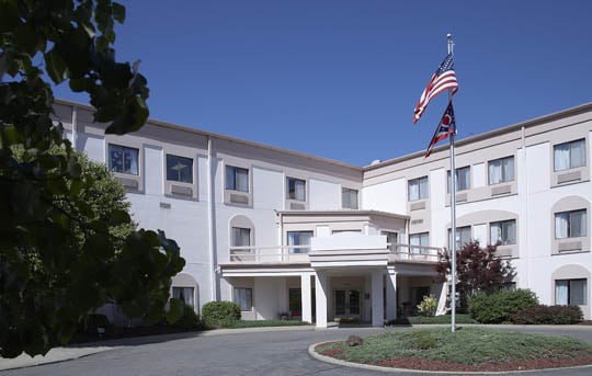 A building with a flagpole displaying American flags in front of an entrance.