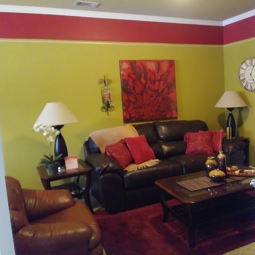A cozy living room with a brown leather sofa and colorful cushions, complemented by a coffee table and decorative wall art.