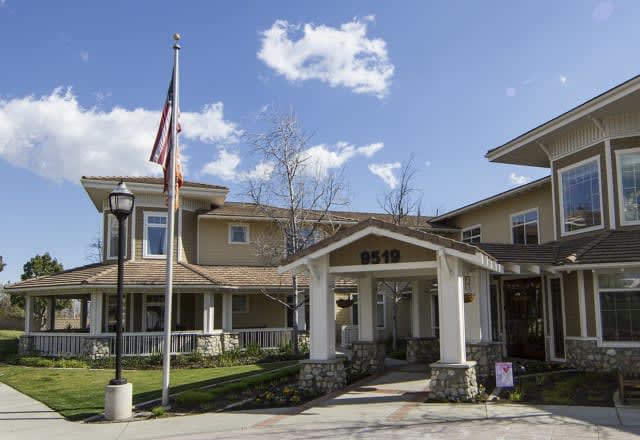 A residential building with an American flag at the entrance on a sunny day.