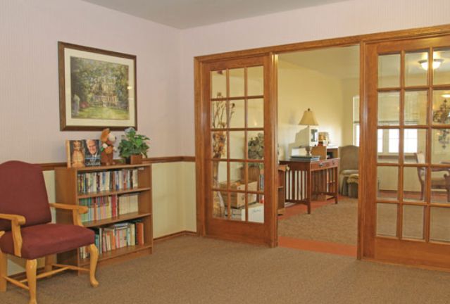 A cozy living room with a bookshelf and French doors opening to another room.