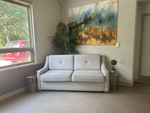A cozy living room featuring a stylish sofa, contemporary artwork, and greenery.