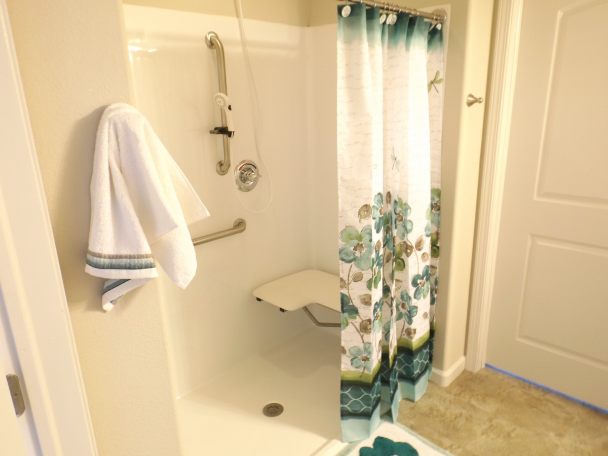 A bathroom featuring a shower with a floral curtain, equipped with a grab bar and folding seat.
