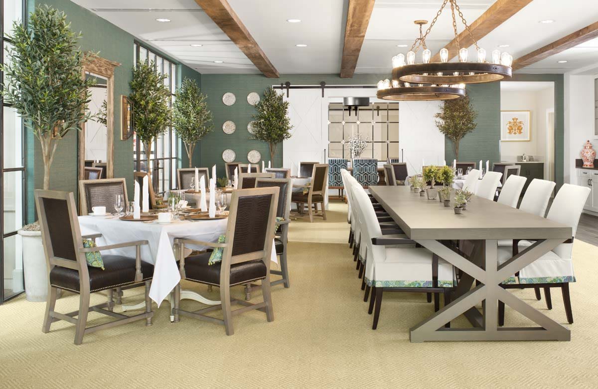 A modern dining room featuring elegant tables, chairs, and sophisticated lighting with greenery accents.