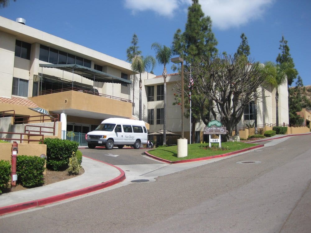 A hospital building with a van parked at the entrance.