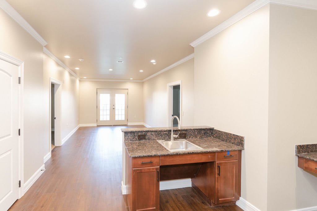 A modern kitchen space with a wooden floor, recessed lighting, and an open layout.