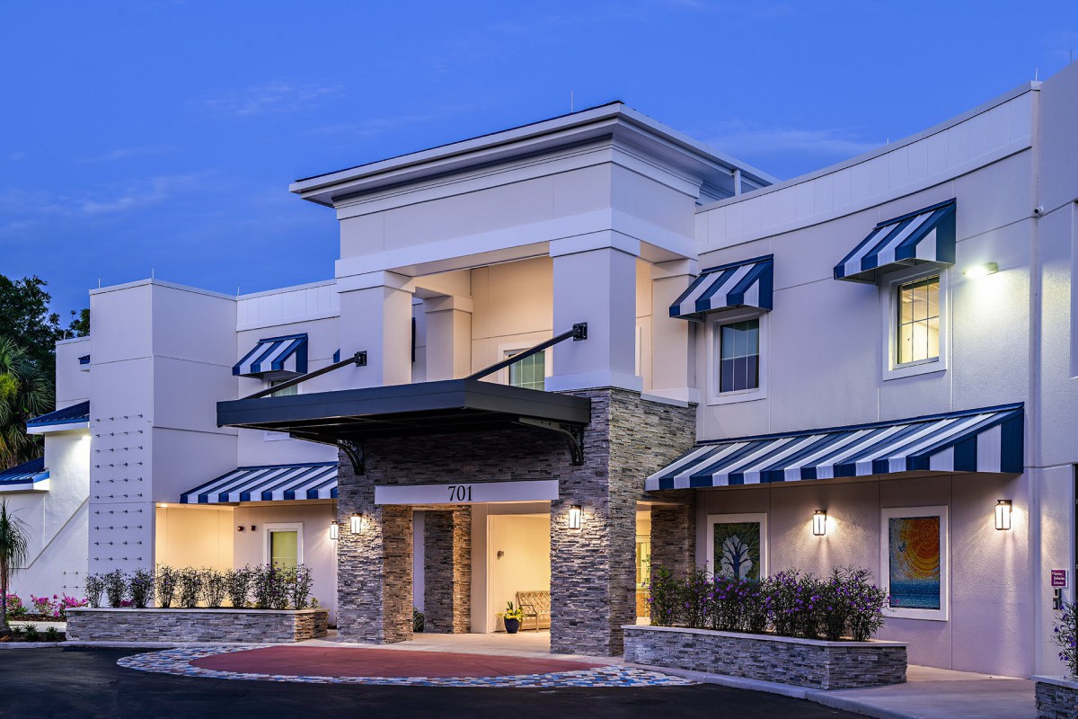 A modern hotel building with striped awnings and a welcoming entrance in the evening.