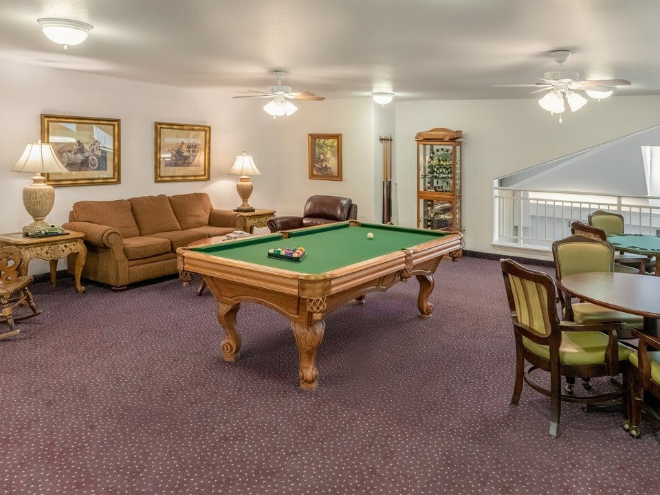 A cozy game room featuring a pool table, comfortable seating, and soft lighting.