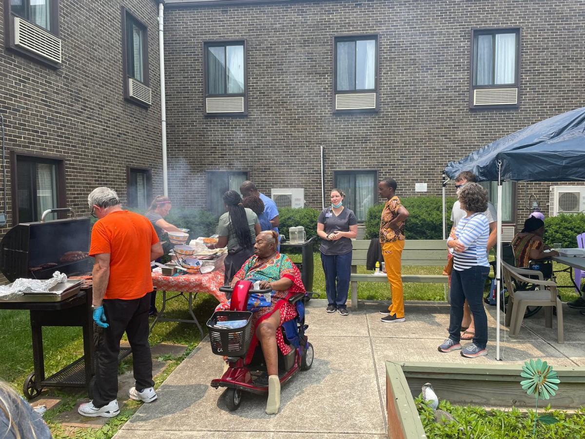 A group of people enjoying a barbecue in an outdoor area beside a building.
